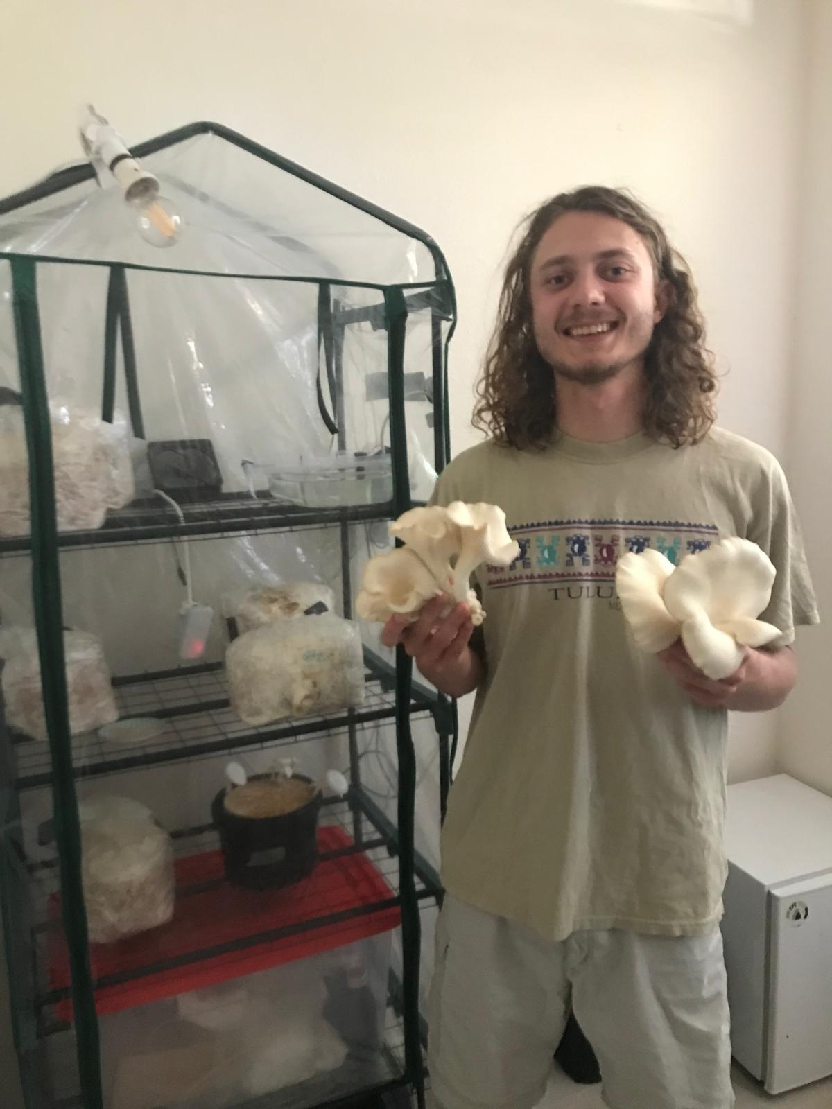 Glimlachende man houdt twee witte botten vast voor een glazen kooi met dierenverblijf en gereedschap.